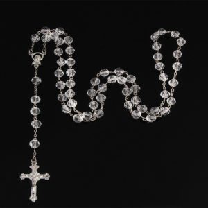 Chapelet catholique en perles blanches transparentes sur fond noir.