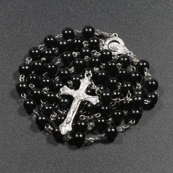 Chapelet catholique noir avec une croix et une estampe de la vierge marie sur fond noir.