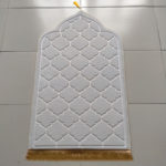 Tapis de prière blanc en forme de porte oriental. Le tissu est molletonné avec des franges en bas et un pompons en haut.