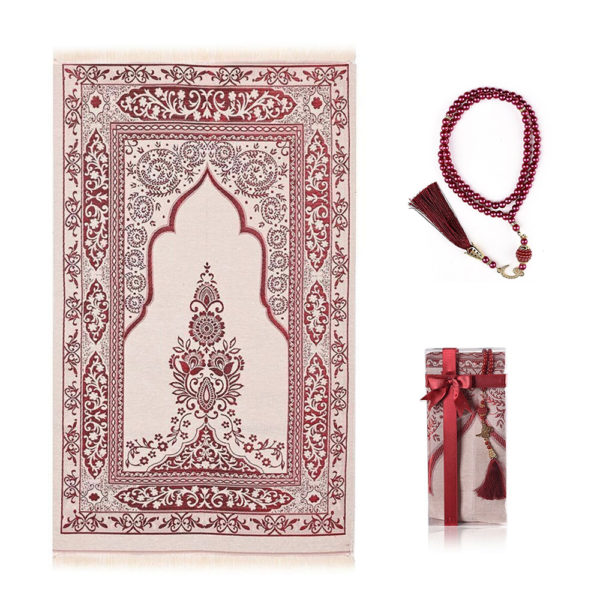 Un tapis de prière rose foncé est étendu sur un fond blanc. Un chapelet assorti est à sa droite et une petite boîte également.
