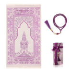 Un tapis de prière violet est étendu sur un fond blanc. Un chapelet assorti est à sa droite et une petite boîte cadeau.