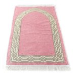 Superbe tapis de prière en coton rose clair à franges blanches. Il y a un motif porte blanc sur le tapis.