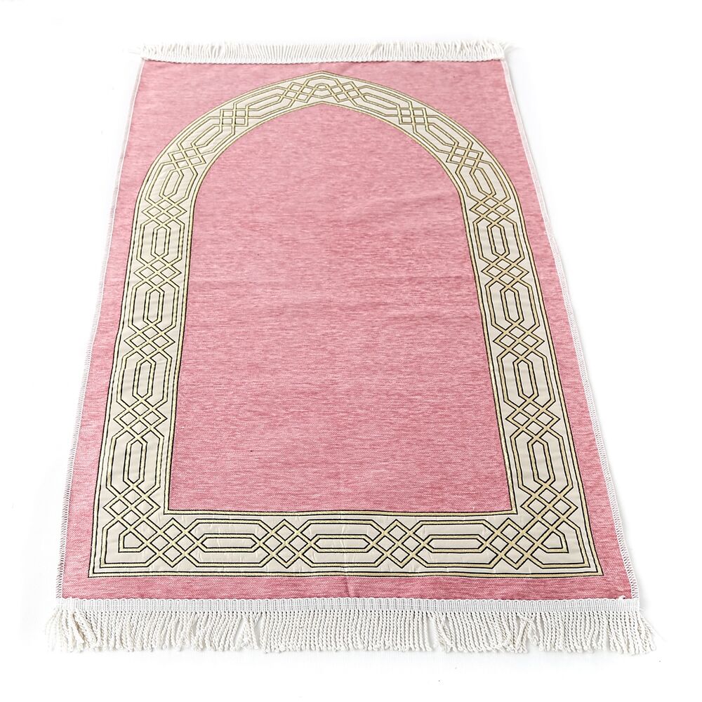 Superbe tapis de prière en coton rose clair à franges blanches. Il y a un motif porte blanc sur le tapis.