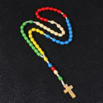 Chapelet catholique en perles de bois colorée avec une croix en bois gravée de Jesus.