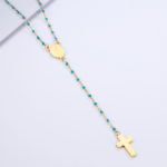 Chapelet catholique avec de petites perles bleues sur une chaine dorées. Un pendentif en croix minimaliste doré et un médaillon doré gravé de la vierge marie
