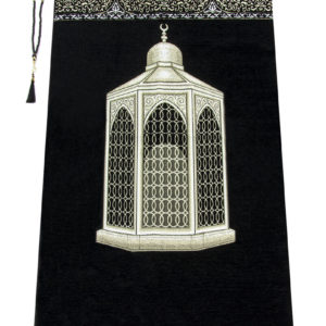 Un tapis noir décoré d'un monument arabe est étendu sur un fond blanc. Il est orné de détails dorés et de franges blanches. Un chapelet de prière est posé sur la gauche.