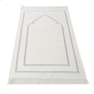 Un tapis blanc est posé sur une fond blanc. Des motifs orientaux ornent le tapis et des franges sont visibles aux extrémités du tapis. Le motif ressemble à une porte d'entrée.