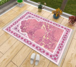 Tapis de prière rose effet marbre. Un tapis luxueux fait en coton et antidérapant. Le tapis est posé sur du parquet avec des chaussons à côté et des fleurs contre la baie-vitrée