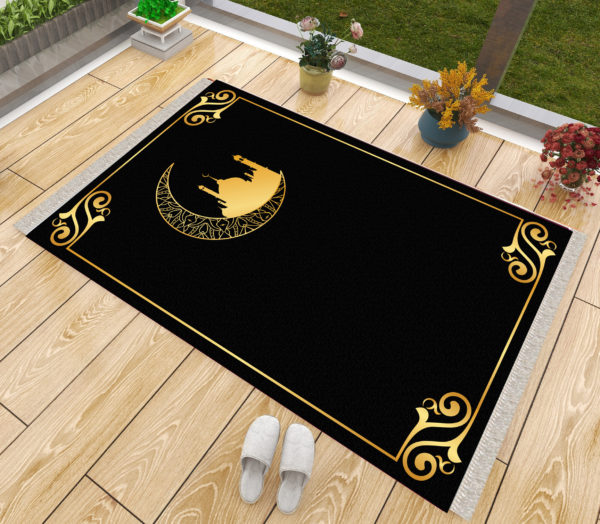 Un tapis de prière noir et doré posé sur du parquet à côté d'une fenêtre. Des chaussons sont posés à côté du tapis ainsi que des pots de fleurs. Le tapis est majoritairement noir et présente des dorures dans les coins et une mosquée dans un croissant de lune.