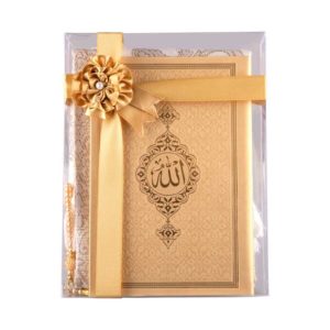 Joli ensemble de prière soigneusement emballé avec un ruban doré et un petit noeud. Le paquet contient un tapis de prière, un Coran et un chapelet doré.