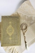 Superbe ensemble d'accessoires de prière dorés : un Coran à la couverture rigide et très élégante, un chapelet doré et un tapis beige et doré très féminin.
