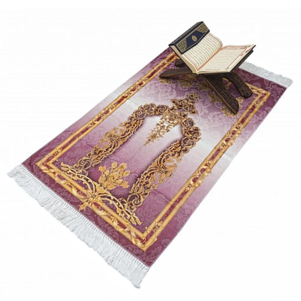 Tapis de prière en coton rose avec des motifs doré Sur le tapis un tabouret est posé avec un livre du coran dessus.