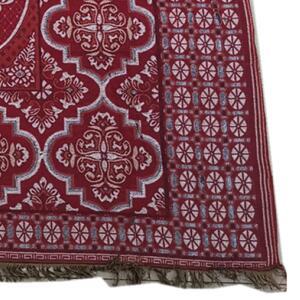 Ca tapis de prière est rouge et rectangulaire avec des motifs et un temps. Il est placé sur un fond blanc.