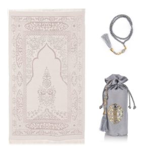 Un tapis de prière gris est étendu sur un fond blanc. Un chapelet assorti est à sa droite et une petite sacoche également.