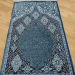 Tapis de prière musulman bleu. Motifs de style persan en nuances de bleu qui forment une porte orientale.
