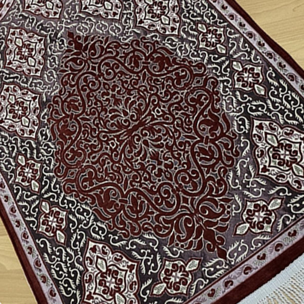 Tapis de prière musulman rouge. Motifs de style persan en nuances de rouge et blanc qui forment une porte orientale.