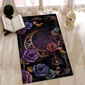 Un tapis de prière est étendue sur un sol en parquet. On distingue une lune et des roses de plusieurs couleurs en motif sur le tapis de prière à fond noir.. Un Coran est ouvert et une lampe est posée sur le sol.