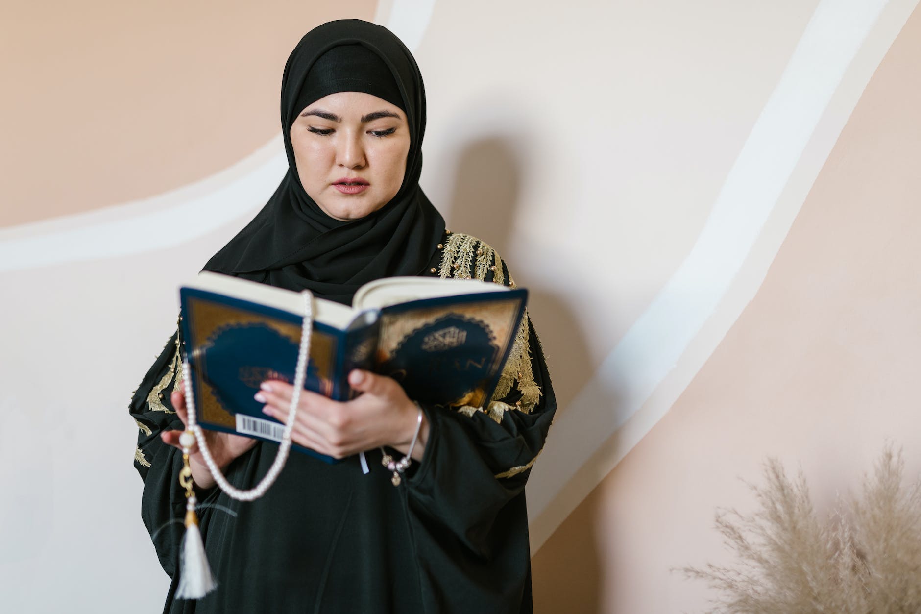 woman in black hijab holding a holy islam book