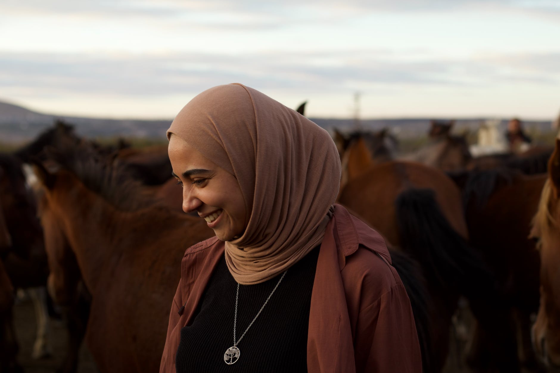 woman in hijab among horses