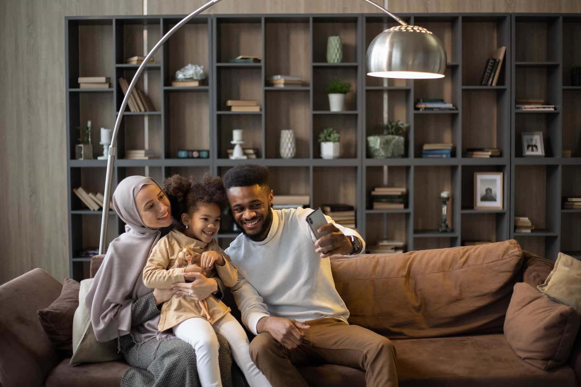 delighted multiethnic family taking selfie sitting on couch